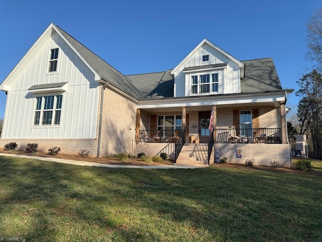 view of front of property featuring board and batten siding, a front yard, covered porch, and brick siding