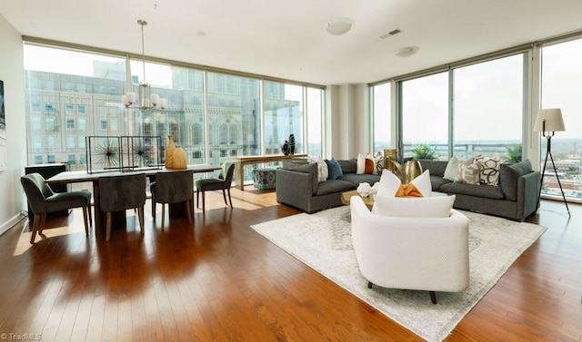 living area featuring dark wood finished floors, a wall of windows, visible vents, and a chandelier