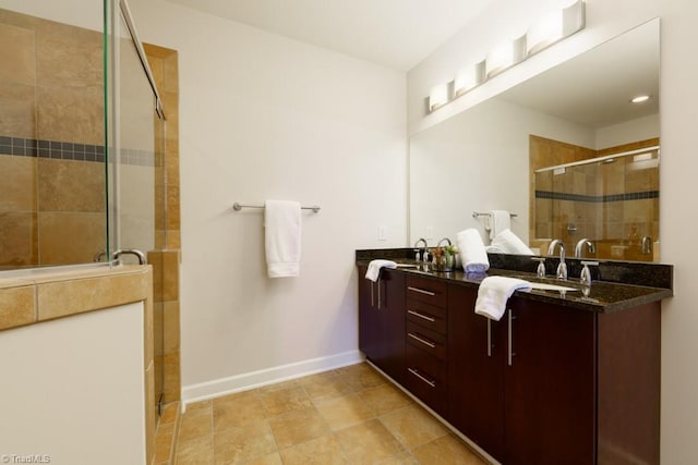 bathroom featuring double vanity, baseboards, a stall shower, and a sink