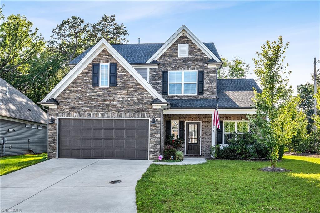 1075 Woodview Ridge Trl Unit 1, Lewisville, NC 27023 - craftsman-style house featuring concrete driveway, a front yard, a garage, and stone siding