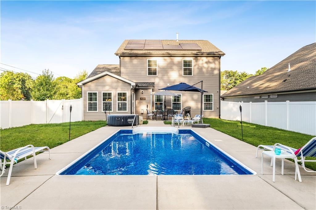 1075 Woodview Ridge Trl Unit 1, Lewisville, NC 27023 - back of property with solar panels, a patio area, a fenced backyard, and a hot tub