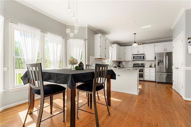 dining space featuring crown molding, baseboards, and light wood finished floors