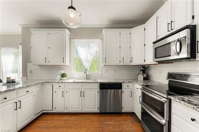 kitchen with crown molding, decorative backsplash, white cabinetry, a sink, and appliances with stainless steel finishes
