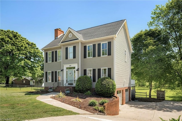 colonial inspired home featuring a front lawn, fence, a chimney, an attached garage, and driveway