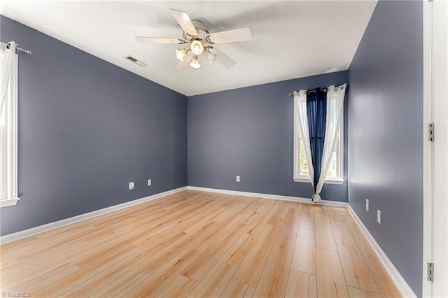 unfurnished room with baseboards, a ceiling fan, light wood-style flooring, and visible vents
