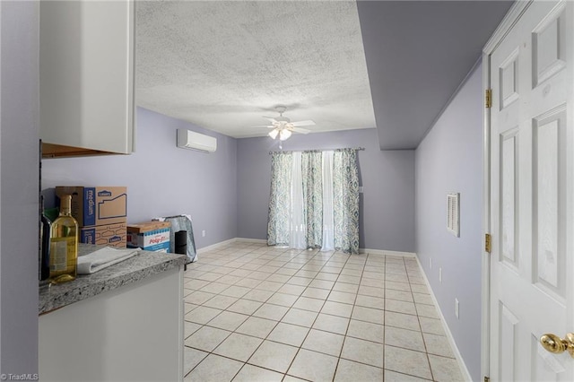 interior space with baseboards, ceiling fan, light countertops, a textured ceiling, and light tile patterned floors