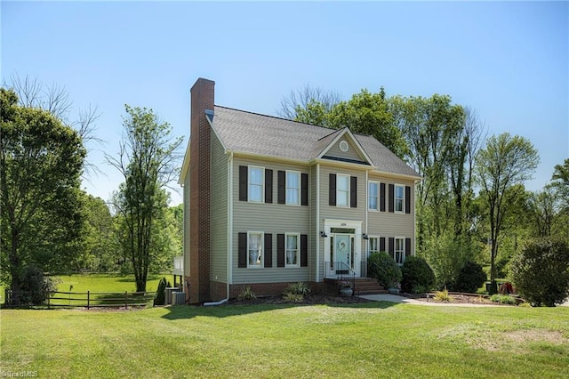 colonial-style house with fence, central air condition unit, a chimney, and a front lawn