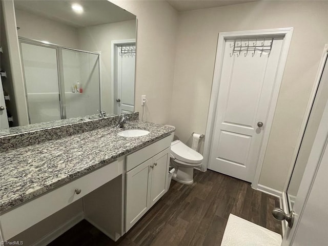 bathroom featuring wood-type flooring, toilet, vanity, and a shower with shower door