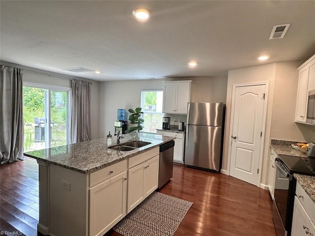 kitchen with stainless steel appliances, sink, white cabinets, and a kitchen island with sink