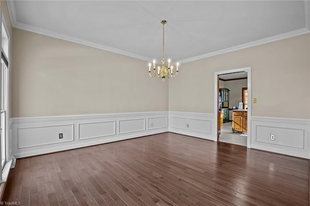 empty room featuring ornamental molding, dark wood-type flooring, and an inviting chandelier