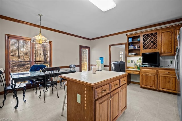 kitchen featuring a breakfast bar, hanging light fixtures, ornamental molding, a notable chandelier, and a kitchen island