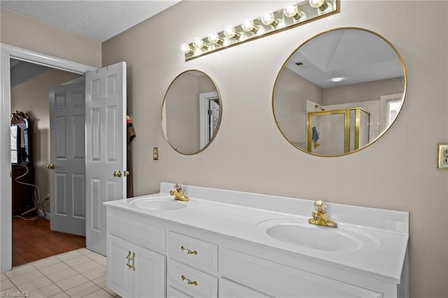 bathroom featuring tile patterned flooring, vanity, an enclosed shower, and a textured ceiling