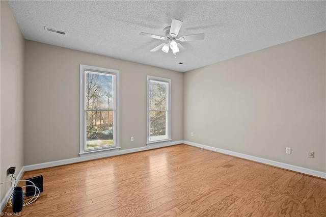 empty room featuring a textured ceiling, light hardwood / wood-style floors, and ceiling fan