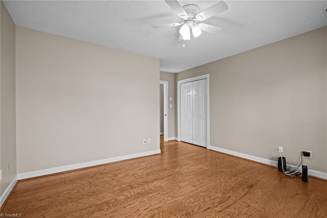 unfurnished room featuring a textured ceiling, light wood-type flooring, and ceiling fan