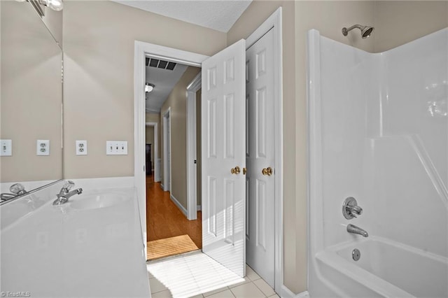 bathroom featuring  shower combination, tile patterned floors, and sink