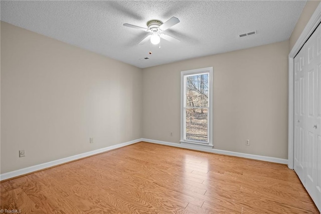 unfurnished bedroom featuring ceiling fan, light hardwood / wood-style floors, a textured ceiling, and a closet