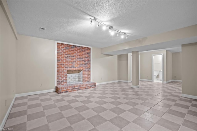 unfurnished living room featuring rail lighting, a textured ceiling, and a brick fireplace