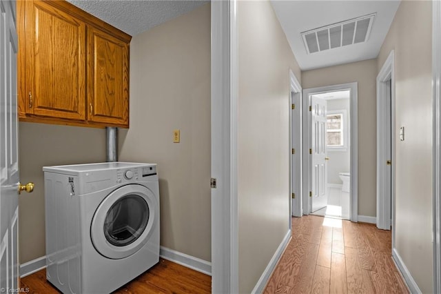 laundry room with cabinets, hardwood / wood-style floors, and washer / clothes dryer