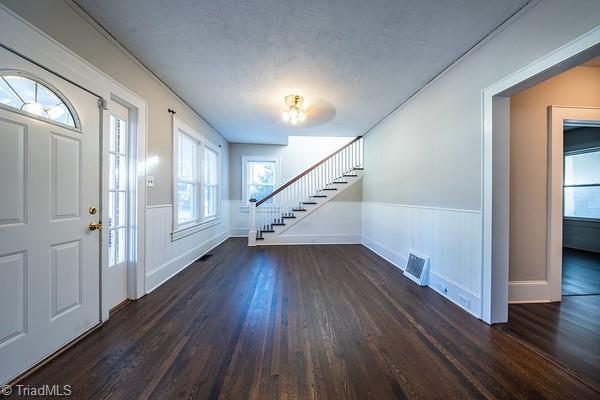 foyer with dark wood-type flooring, plenty of natural light, and a textured ceiling