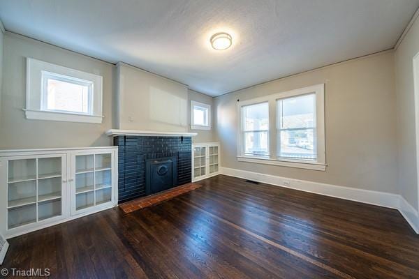 unfurnished living room with a brick fireplace and dark hardwood / wood-style flooring