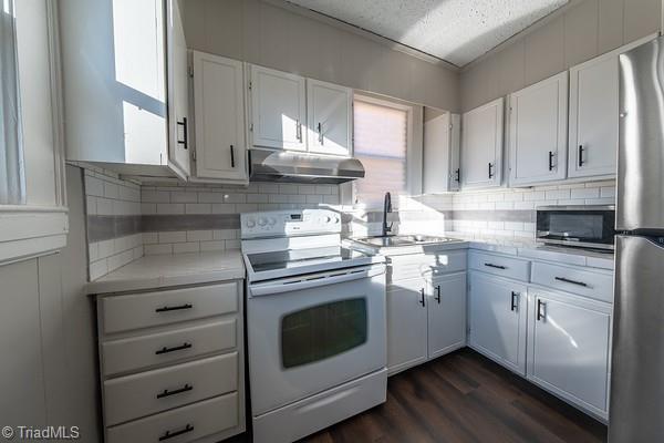 kitchen with decorative backsplash, sink, stainless steel appliances, white cabinets, and dark hardwood / wood-style flooring