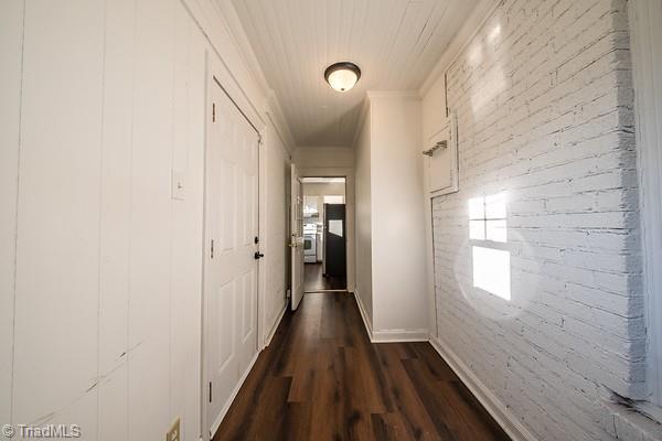 corridor with brick wall and dark hardwood / wood-style floors