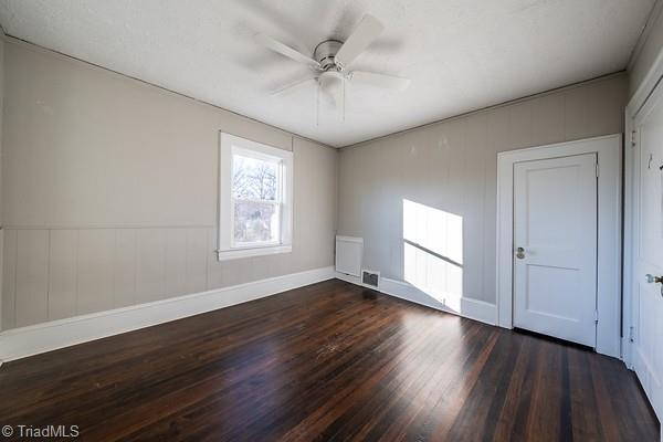 unfurnished room with dark wood-type flooring, radiator heating unit, and ceiling fan