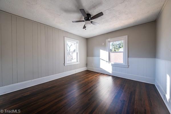 spare room featuring ceiling fan, dark hardwood / wood-style floors, and a textured ceiling