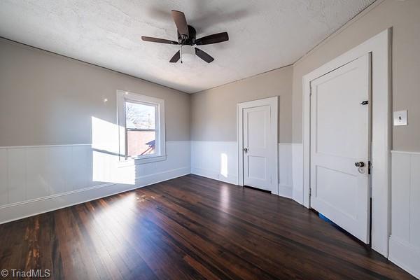 unfurnished room with ceiling fan, dark hardwood / wood-style flooring, and a textured ceiling