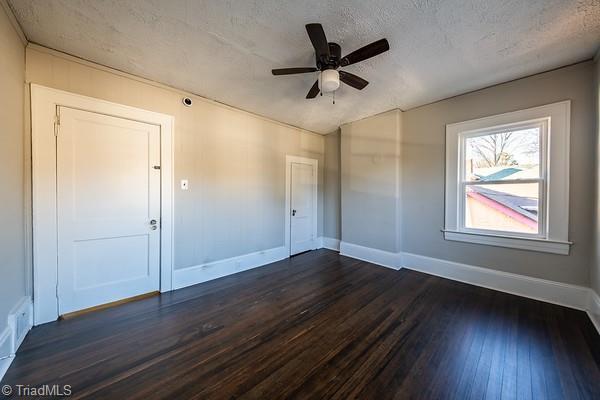 unfurnished room with a textured ceiling, ceiling fan, and dark hardwood / wood-style flooring