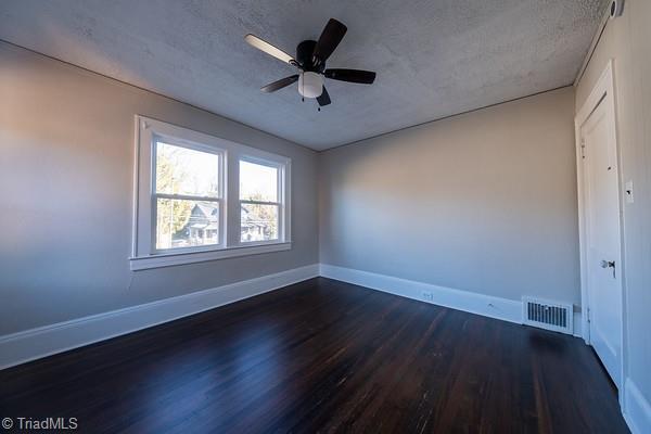 unfurnished room with ceiling fan, a textured ceiling, and dark hardwood / wood-style floors