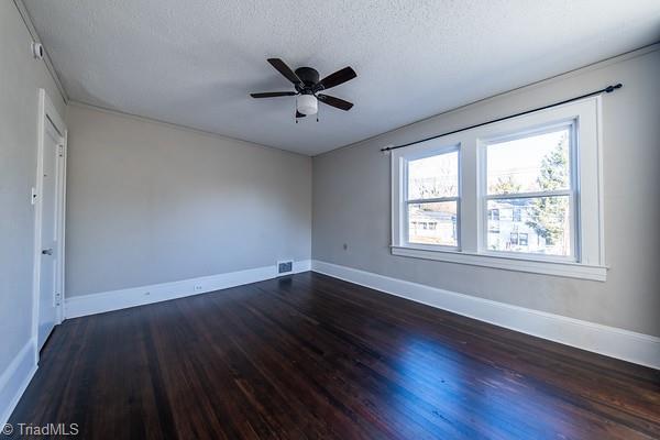 unfurnished room featuring a textured ceiling, dark wood-type flooring, and ceiling fan