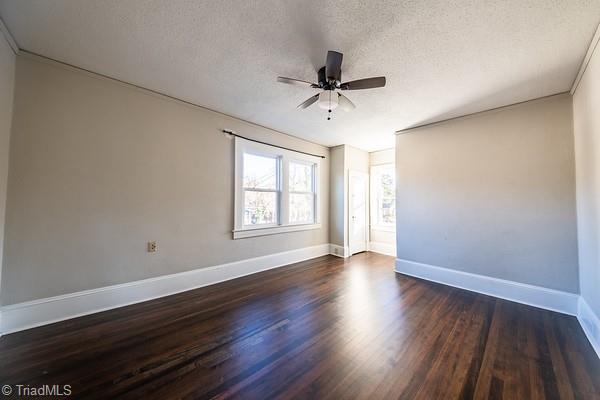 unfurnished room featuring ceiling fan, dark wood-type flooring, and a textured ceiling