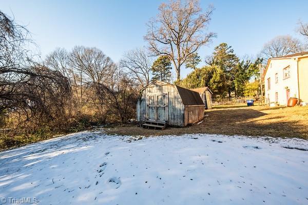 yard covered in snow featuring a storage shed