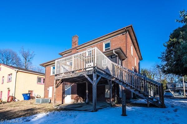 snow covered rear of property with a wooden deck and central air condition unit