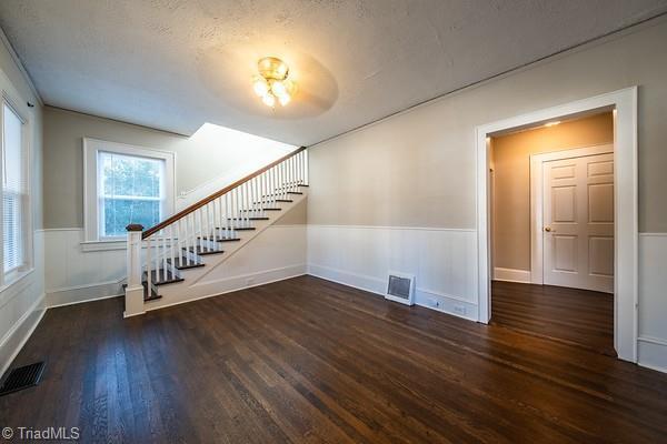 unfurnished living room with a textured ceiling and dark hardwood / wood-style floors