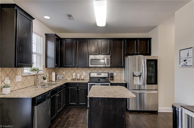 kitchen with appliances with stainless steel finishes, dark hardwood / wood-style floors, sink, and a kitchen island