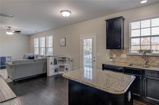 kitchen with a center island, decorative backsplash, dark hardwood / wood-style flooring, black dishwasher, and sink