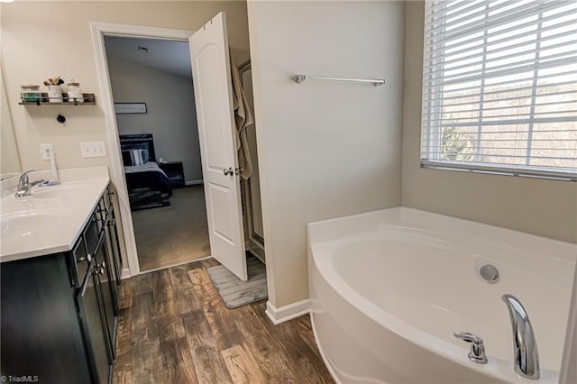 bathroom featuring wood-type flooring, vanity, and a bath