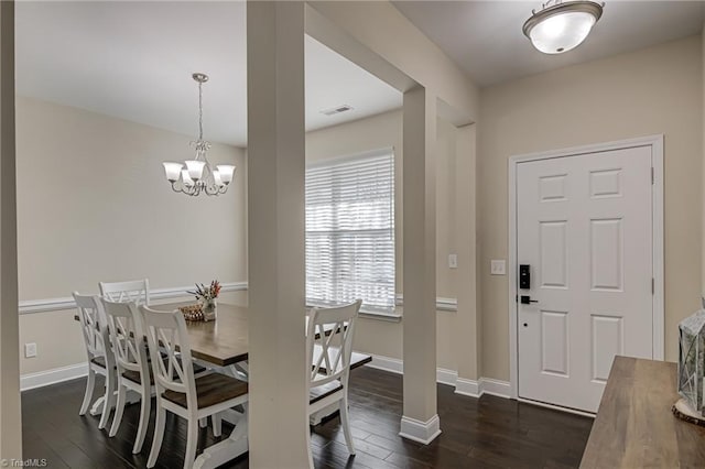 dining area with dark wood-type flooring and an inviting chandelier