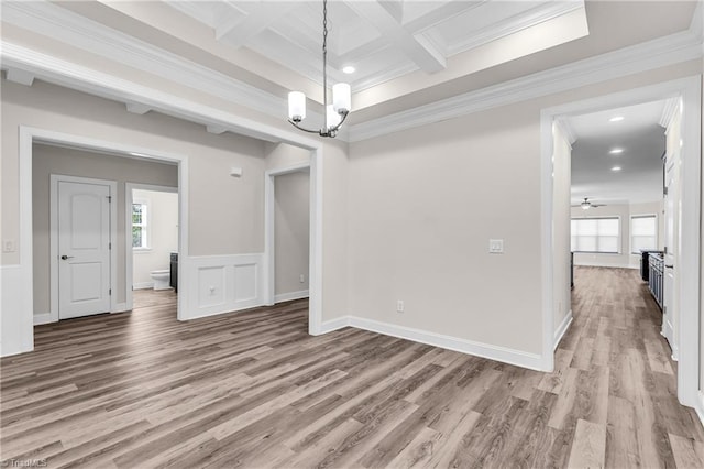 unfurnished dining area featuring a wealth of natural light, ceiling fan with notable chandelier, coffered ceiling, and hardwood / wood-style floors