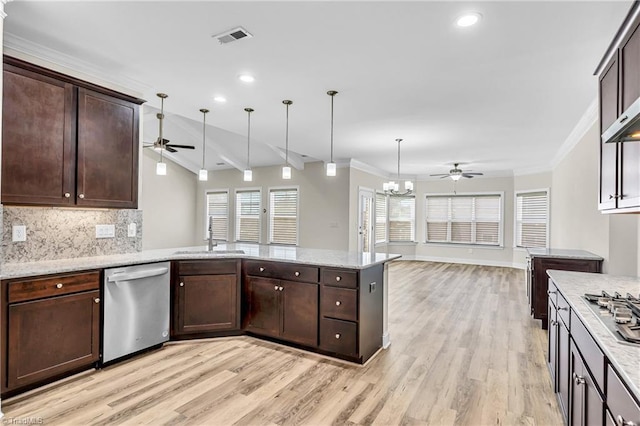 kitchen featuring stainless steel appliances, sink, hanging light fixtures, vaulted ceiling, and light stone counters