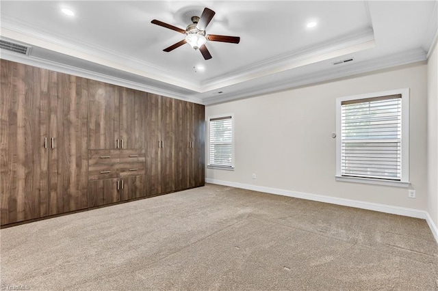 carpeted spare room with ceiling fan, a wealth of natural light, and a raised ceiling