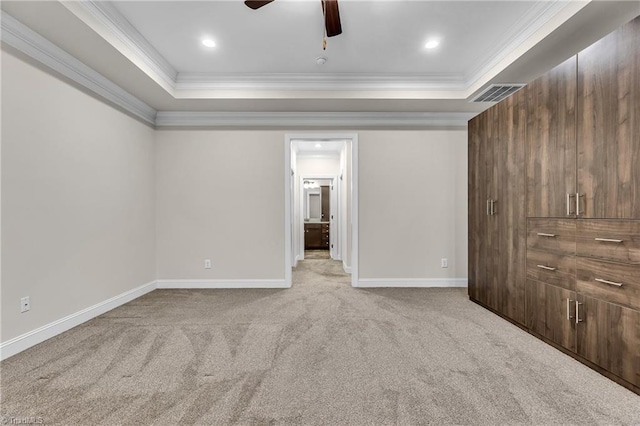 unfurnished room with ceiling fan, light colored carpet, a tray ceiling, and crown molding