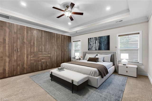 carpeted bedroom with ceiling fan, ornamental molding, and a raised ceiling