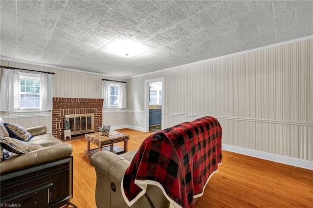 living room featuring light hardwood / wood-style flooring, ornamental molding, and a fireplace