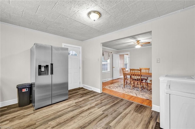 kitchen with ceiling fan, wood-type flooring, stainless steel fridge with ice dispenser, independent washer and dryer, and crown molding