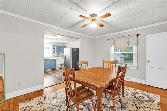 dining area featuring wood-type flooring, crown molding, and ceiling fan