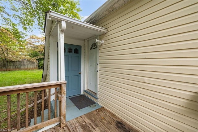 view of exterior entry with a yard and a deck