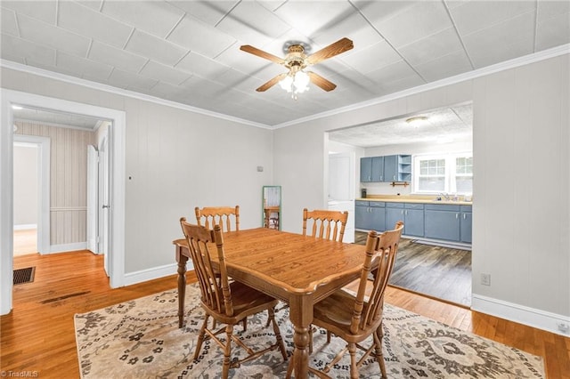 dining space with ceiling fan, hardwood / wood-style flooring, crown molding, and sink